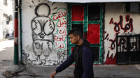 A man walks near a mural of Handala in the village of al-Fara, in the occupied West Bank, following an Israeli raid on Dec. 8.